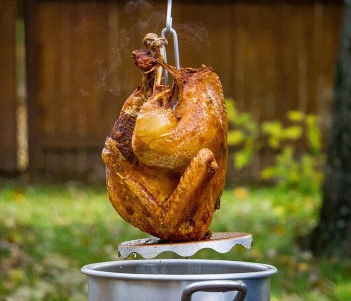turkey being lowered into a deep fryer outdoors